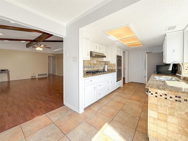 kitchen featuring light tile patterned flooring, sink, beam ceiling, white cabinetry, and stainless steel appliances