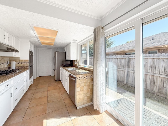 kitchen with stone counters, appliances with stainless steel finishes, white cabinetry, sink, and light tile patterned floors