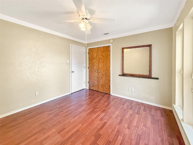 empty room with ceiling fan, ornamental molding, a textured ceiling, and hardwood / wood-style flooring