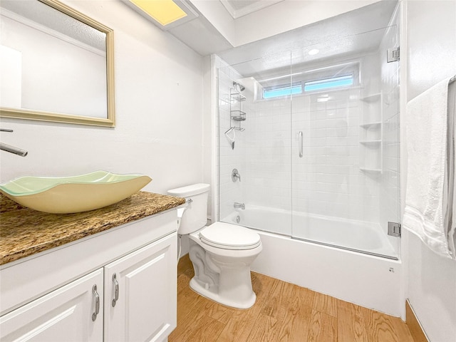 full bathroom featuring enclosed tub / shower combo, wood-type flooring, toilet, and vanity