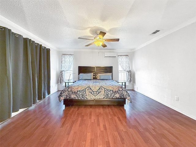 bedroom featuring a wall mounted AC, a textured ceiling, ornamental molding, ceiling fan, and hardwood / wood-style floors