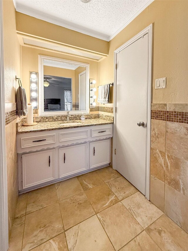 bathroom with vanity, a textured ceiling, tile walls, and ornamental molding