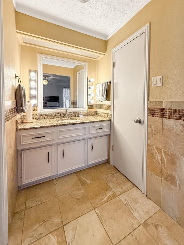 bathroom featuring vanity, crown molding, tile walls, and a textured ceiling