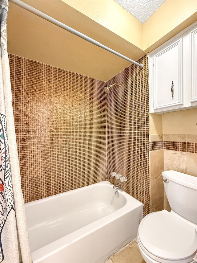 bathroom featuring toilet, tile walls, a textured ceiling, shower / bathtub combination with curtain, and tile patterned flooring