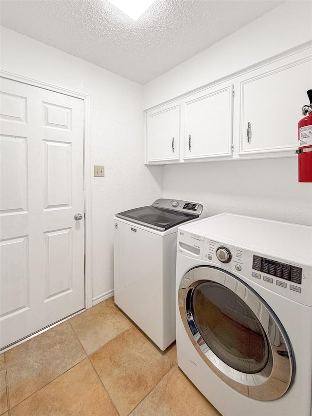 laundry room with cabinets, a textured ceiling, and washing machine and clothes dryer