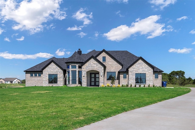 french country inspired facade featuring a front yard and french doors