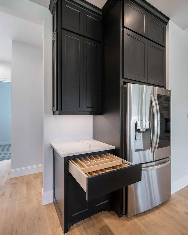 kitchen featuring light stone counters, stainless steel fridge with ice dispenser, and light wood-type flooring