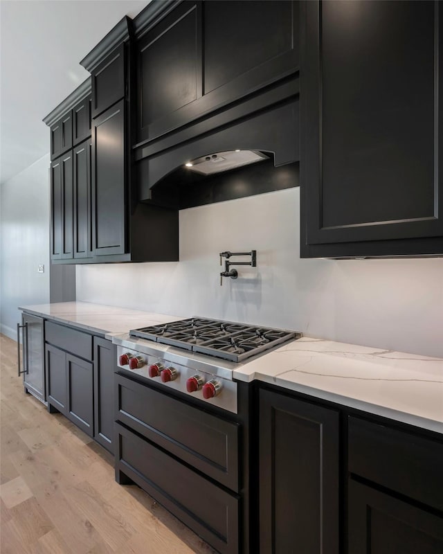 kitchen featuring stainless steel gas cooktop, custom exhaust hood, light hardwood / wood-style flooring, beverage cooler, and light stone countertops