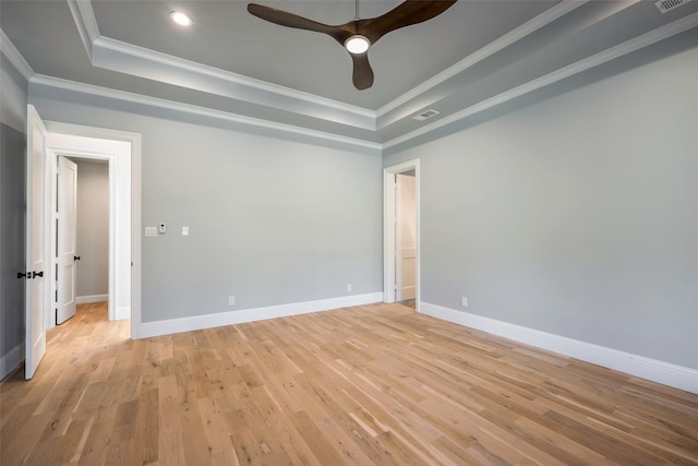 empty room featuring crown molding, light hardwood / wood-style flooring, and a tray ceiling