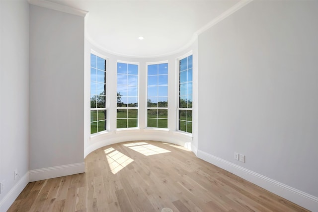 empty room with ornamental molding and light wood-type flooring