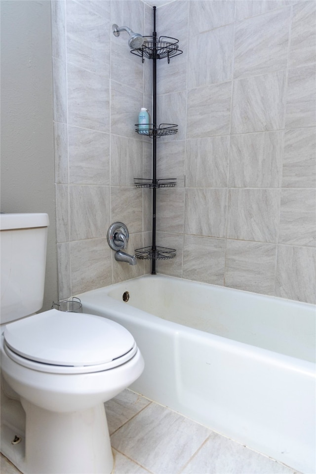 bathroom featuring tile patterned flooring, tiled shower / bath combo, and toilet