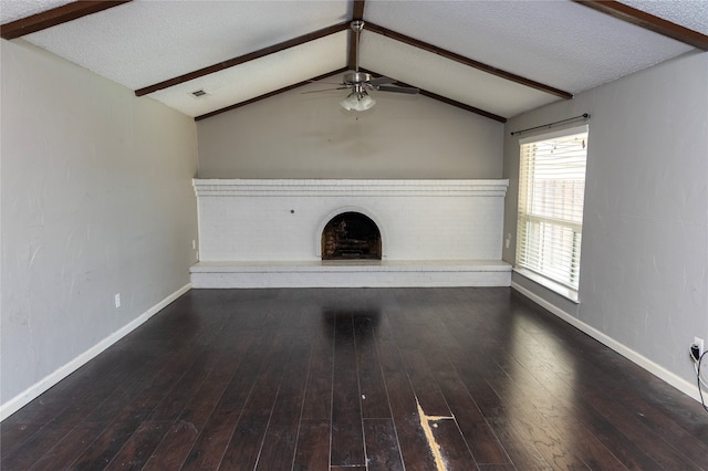 unfurnished living room with dark hardwood / wood-style floors, lofted ceiling with beams, a textured ceiling, and a brick fireplace