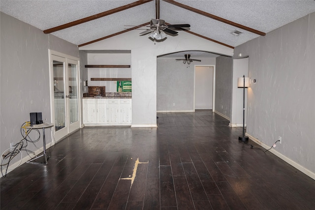 unfurnished living room with french doors, lofted ceiling with beams, and a textured ceiling