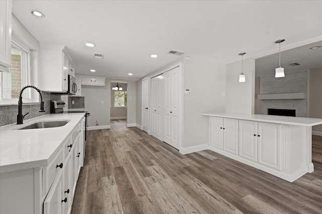 kitchen featuring visible vents, a sink, a fireplace, and wood finished floors