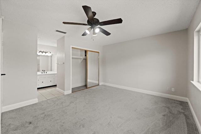 unfurnished bedroom featuring a sink, a textured ceiling, visible vents, and carpet flooring