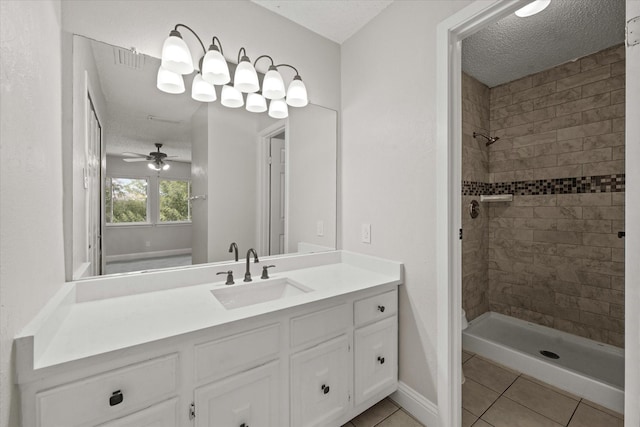 bathroom with a tile shower, ceiling fan, tile patterned flooring, a textured ceiling, and vanity