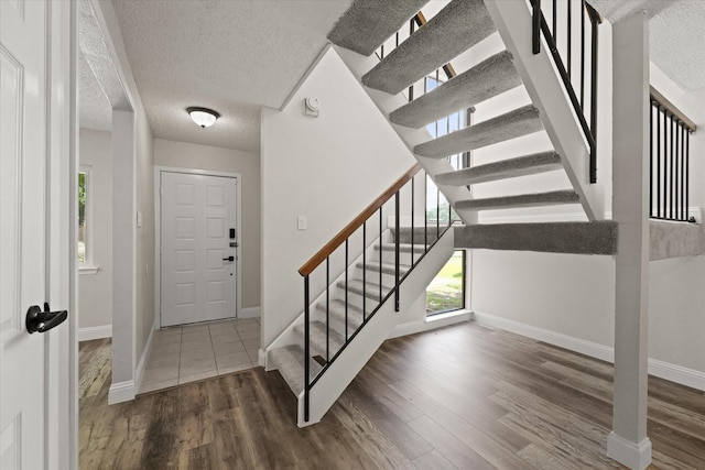 foyer entrance featuring a textured ceiling and dark wood-type flooring