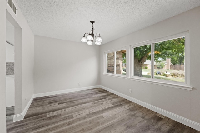 unfurnished room featuring hardwood / wood-style floors, a textured ceiling, and an inviting chandelier