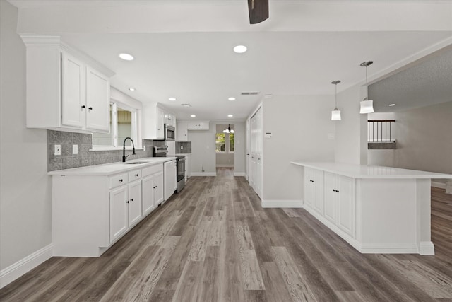 kitchen featuring sink, stainless steel appliances, kitchen peninsula, white cabinets, and hardwood / wood-style flooring