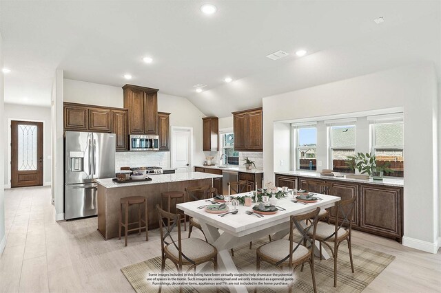 kitchen with light stone counters, a center island, light hardwood / wood-style floors, a fireplace, and ceiling fan