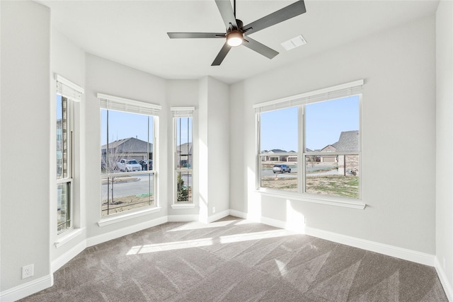 unfurnished room with a healthy amount of sunlight, ceiling fan, and carpet