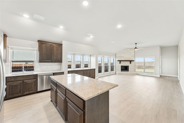 kitchen with a center island, ceiling fan, a fireplace, sink, and stainless steel dishwasher