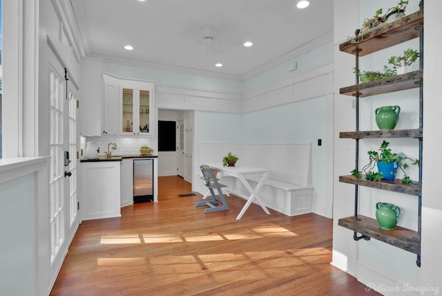 kitchen featuring tasteful backsplash, white cabinets, dark countertops, glass insert cabinets, and ornamental molding