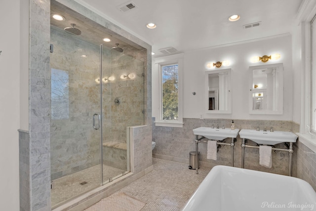 bathroom with sink, plus walk in shower, tile patterned floors, tile walls, and ornamental molding