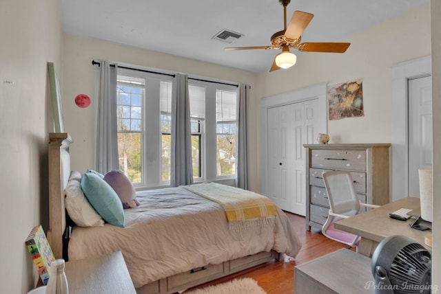 bedroom featuring wood finished floors, visible vents, and a ceiling fan