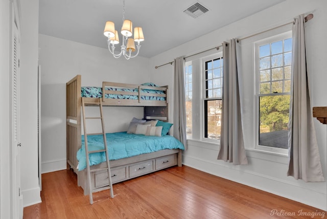 bedroom with multiple windows, a notable chandelier, visible vents, and wood finished floors