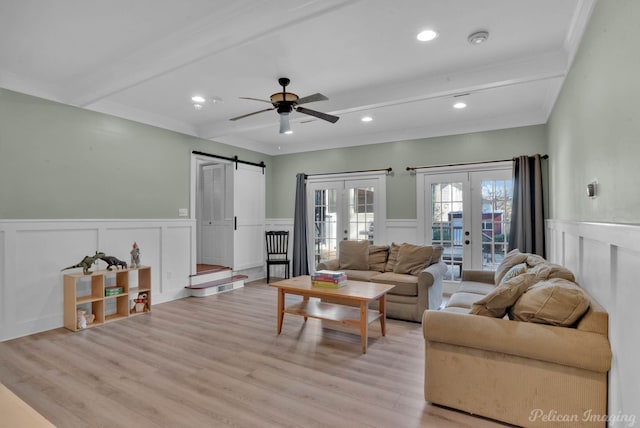 living room with beamed ceiling, a barn door, light wood-type flooring, and french doors