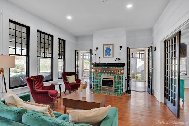 living room featuring light wood-style floors, recessed lighting, and a tiled fireplace