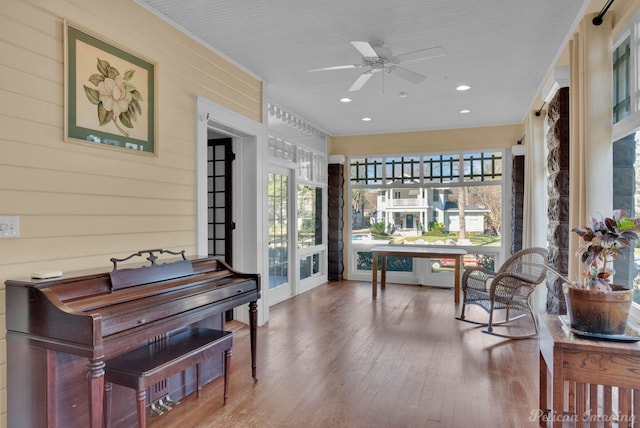 interior space featuring ceiling fan, wood-type flooring, and wood walls