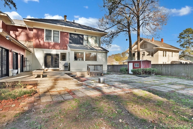 rear view of property with a patio, a fenced backyard, a storage unit, a deck, and an outdoor structure