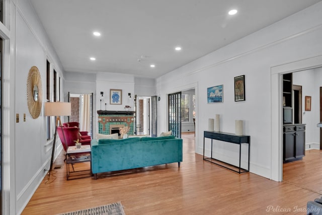 living area with baseboards, a brick fireplace, light wood-style flooring, and recessed lighting