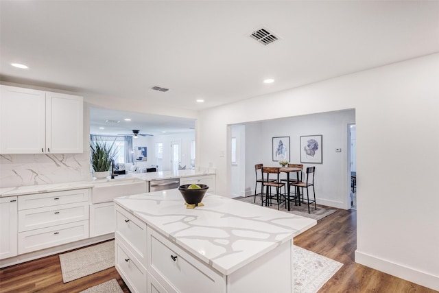 kitchen with white cabinetry, a center island, dishwasher, dark wood-type flooring, and tasteful backsplash