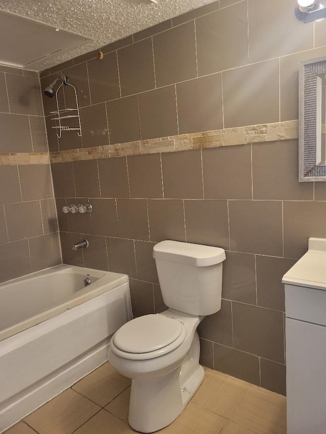 full bathroom with toilet, vanity, tile walls, tile patterned flooring, and washtub / shower combination