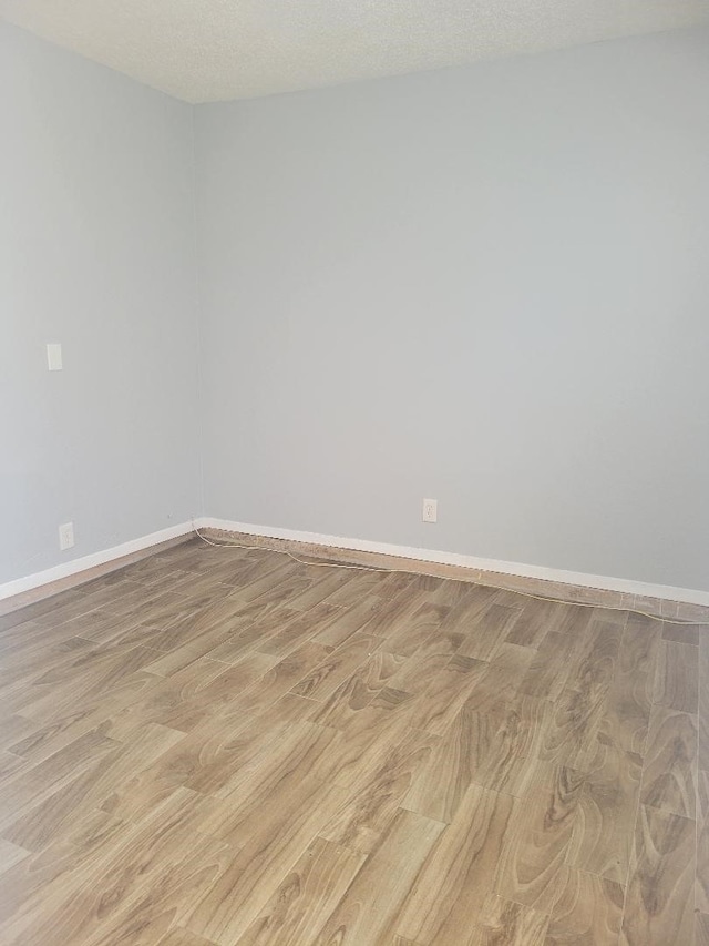 unfurnished room with a textured ceiling and light hardwood / wood-style flooring