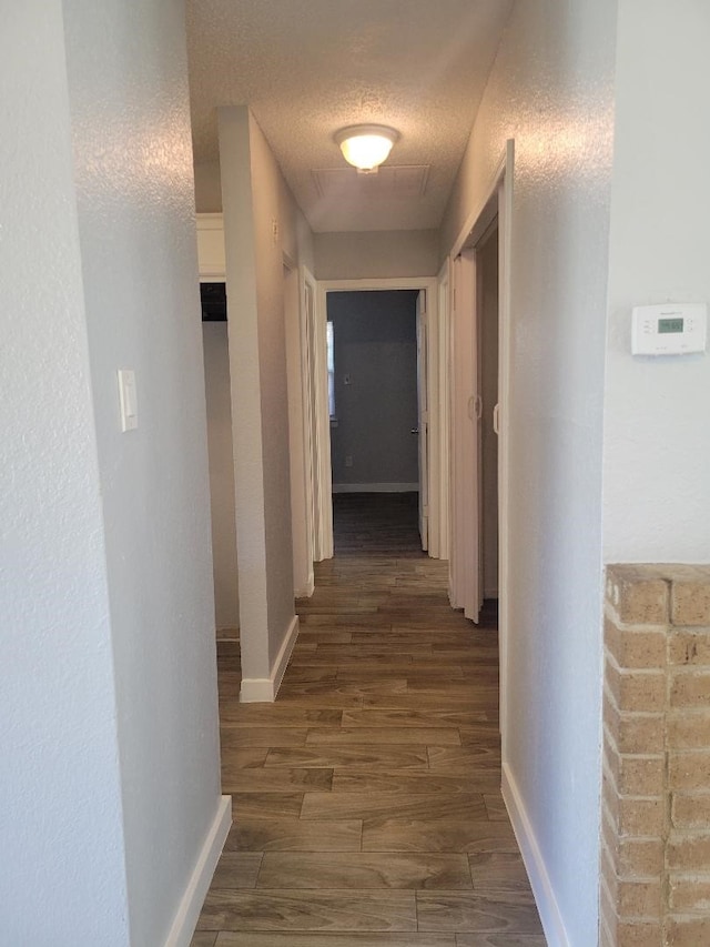 corridor featuring dark hardwood / wood-style flooring and a textured ceiling