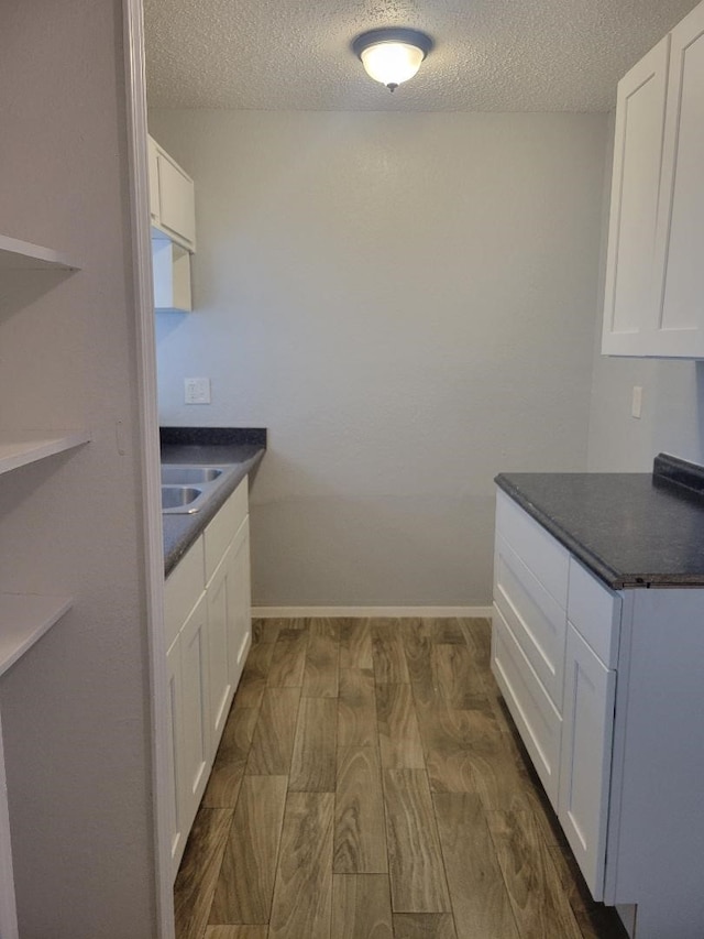 kitchen featuring a textured ceiling, sink, white cabinets, and dark hardwood / wood-style floors