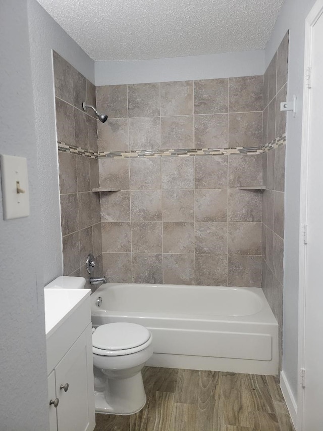 full bathroom featuring toilet, a textured ceiling, vanity, and tiled shower / bath combo