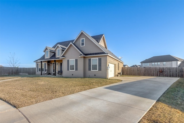 view of front of home featuring covered porch, a garage, and a front lawn