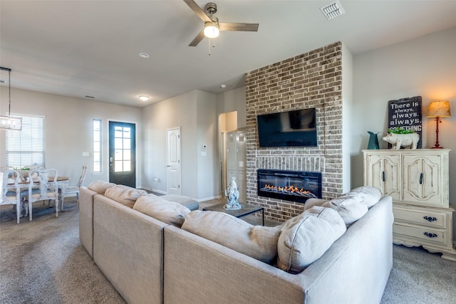 carpeted living room with ceiling fan and a fireplace