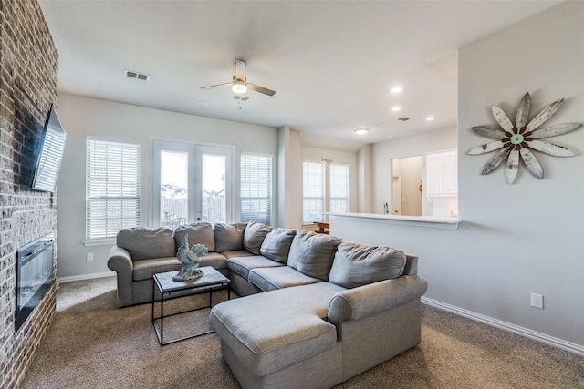 carpeted living room featuring ceiling fan and a fireplace