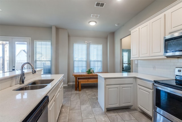 kitchen with light tile patterned floors, stainless steel appliances, backsplash, white cabinets, and sink