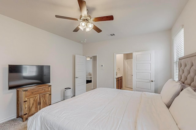 bedroom with ceiling fan, ensuite bath, and light colored carpet