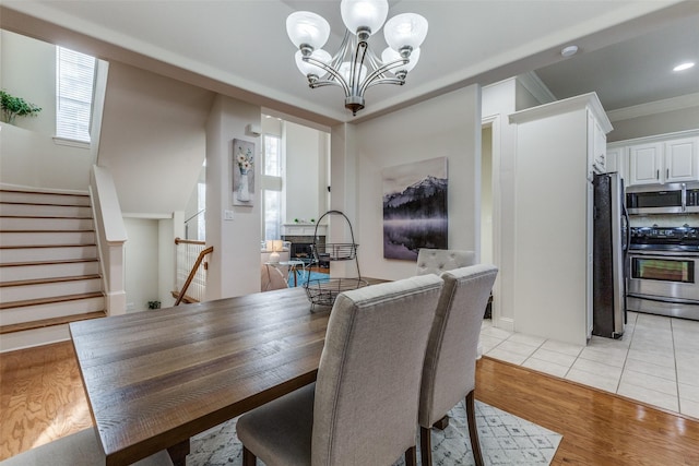 dining space featuring a notable chandelier, a healthy amount of sunlight, ornamental molding, and light hardwood / wood-style flooring