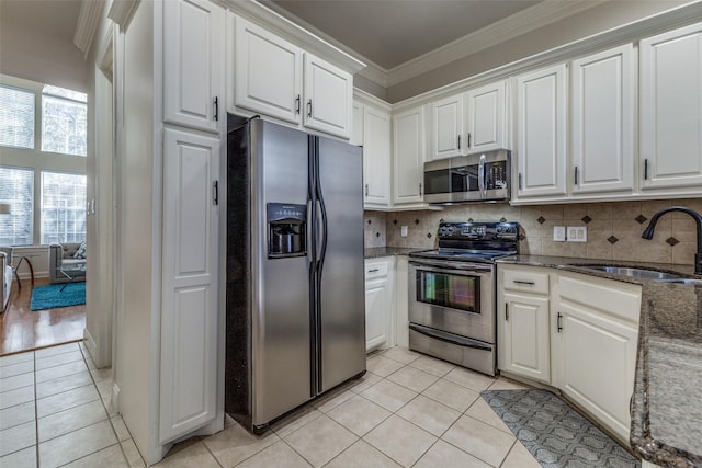 kitchen with white cabinets, stainless steel appliances, light tile patterned flooring, and sink