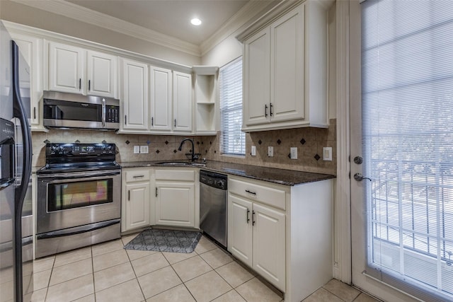 kitchen with white cabinets, sink, dark stone countertops, light tile patterned floors, and stainless steel appliances