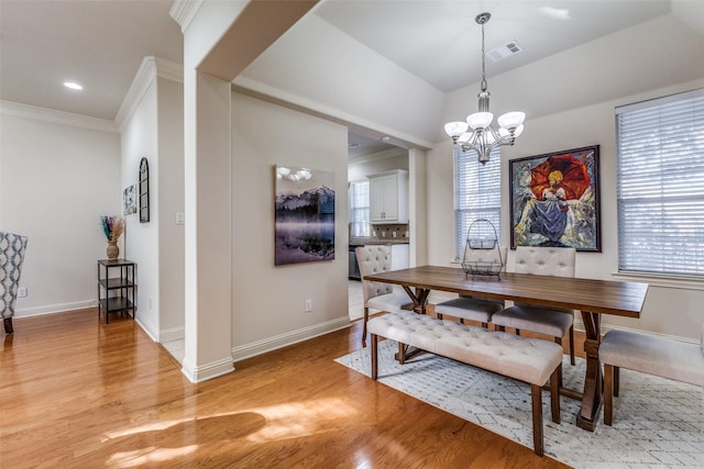 dining space featuring a chandelier, light wood-type flooring, and crown molding